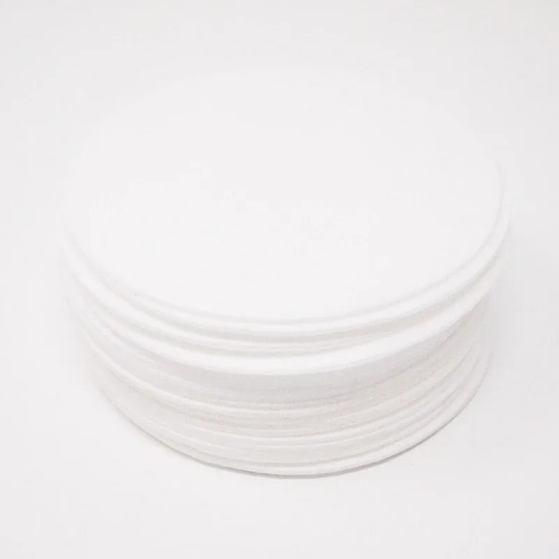 A neat stack of round white synthetic filter discs on a white surface